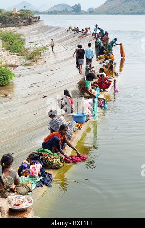 Indische Frauen und Mädchen, die Wäsche von Hand in einem See. Andhra Pradesh, Indien Stockfoto