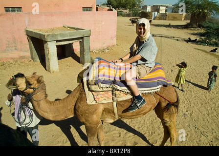 Europäische Junge sitzt auf einem Kamel in der Thar-Wüste, in der Nähe von Bikaner, Rajasthan, Indien