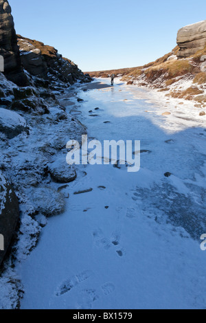 Ein Walker auf den zugefrorenen Fluss Kinder, Winter auf Kinder Scout im Dunkeln Peak Teil der Peak District National Park, Derbyshire Stockfoto