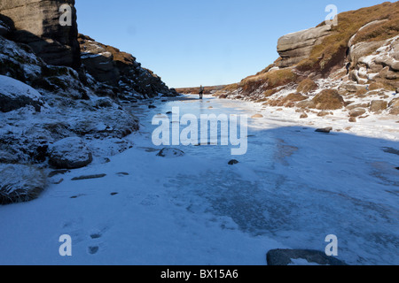 Ein Wanderer auf dem Kinder-Fluss im Winter auf Kinder Scout im Dunkeln Peak Teil der Peak District National Park, Derbyshire, UK Stockfoto