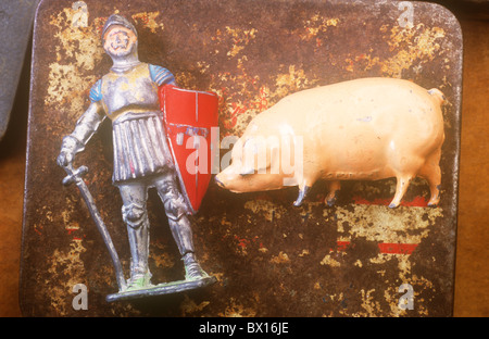 Nahaufnahme von zerkratzten Metall Blei Modelle der Ritter in Rüstung mit Schwert und Schild und große rosa Schwein auf rostigen Zinn Stockfoto