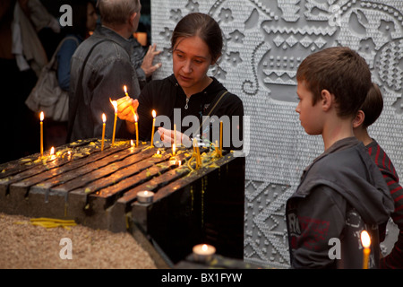 Eine Mutter und ihre Kinder zünden eine Kerze für die Opfer der Hungersnot von 1932-1933 im Holodomor-Museum in Kiew, Ukraine Stockfoto