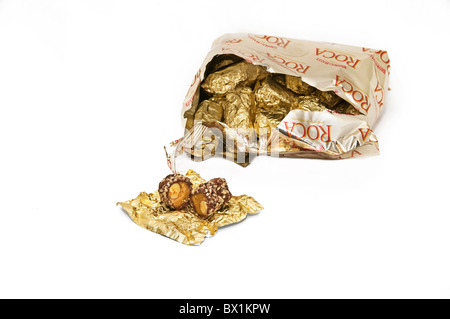 Eine offenere Stück Almond Roca Candy vor einem offenen Beutel gefüllt mit Goldfolie sitzt gewickelt Stücke. Stockfoto