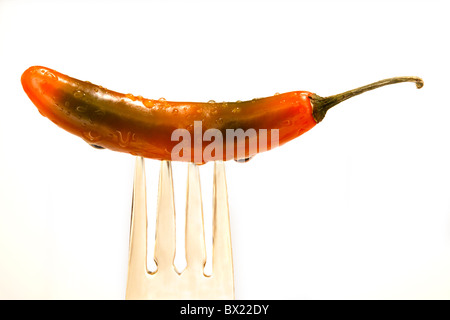 Eine teilweise grün, gelb, rot, nass, Jalapeño-Pfeffer ist eine goldene Gabel auf einem schwarzen Hintergrund beigefügt. Stockfoto