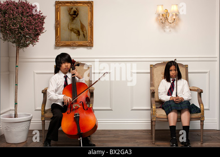 Vietnamesische Kinder mit Musikinstrumenten auf elegante Stühle sitzen Stockfoto