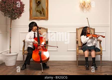 Vietnamesische Kinder mit Musikinstrumenten auf elegante Stühle sitzen Stockfoto