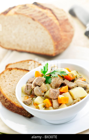 Schüssel mit herzhaften Rindfleisch-Eintopf mit Gemüse serviert mit Roggenbrot Stockfoto
