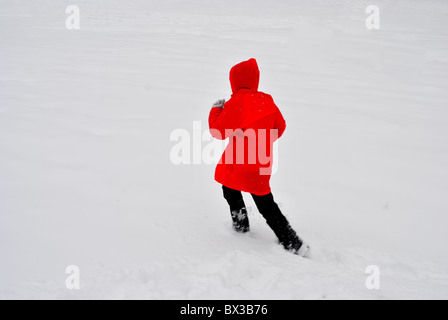 Mädchen mit roten Jacke laufen im Schnee Stockfoto