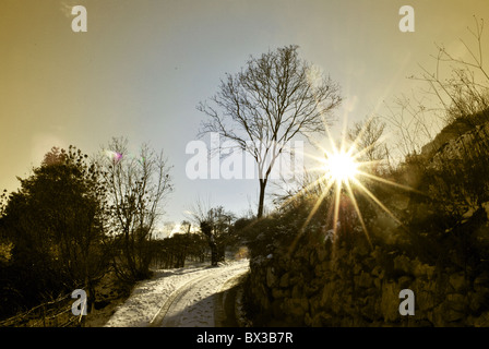 Sonnenuntergang mit Sonne im verschneiten Bergstraße Stockfoto