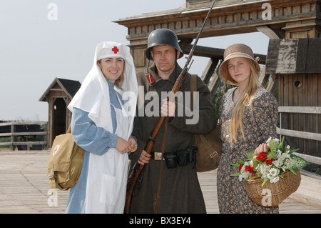 Alten Stil Bild mit Frau in Krankenschwester Kostüm, Mann in Soldat uniform mit Waffe und ihrer Tochter in geblümten Kleid. Kostüme ein Stockfoto