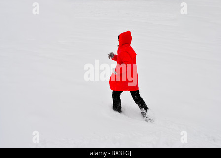 Mädchen mit roten Jacke laufen im Schnee Stockfoto