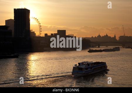 Sonnenuntergang hinter einem hohen Gebäude, Blick über den Fluss Themse als Boote auf die Skyline von Southbank vorbei. Stockfoto