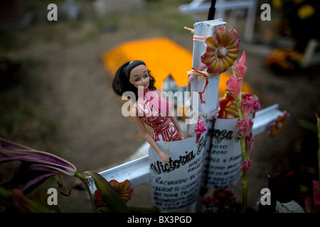 Eine Barbie-Puppe ziert das Kreuz von einem Grab auf dem Friedhof in San Gregorio Atlapulco, Xochimilco, Mexiko-Stadt. Stockfoto
