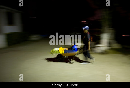 Ein Mann trägt ein Kind und Blumen in einer Schubkarre auf dem Friedhof in San Gregorio Atlapulco, Xochimilco, Mexiko-Stadt Stockfoto