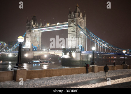 Nachtaufnahme der Tower Bridge in London an einem kalten Winterabend als Schnee liegt in der Luft und durch starken Wind geblasen. Stockfoto