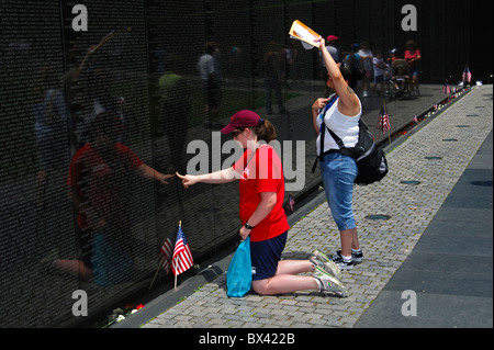 Besucher auf der Suche nach Namen von Verwandten und Freunden in der Name-Panels, Vietnam Veterans Memorial Wall, Washington, D.C., USA Stockfoto