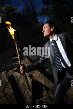 Bild der eleganten Mann hält brennenden Stock während der Bewegung in der Dunkelheit Stockfoto