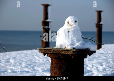 Schneemann auf Resten der West Pier nach seltenen Schneefall am Strand von Brighton, UK Stockfoto