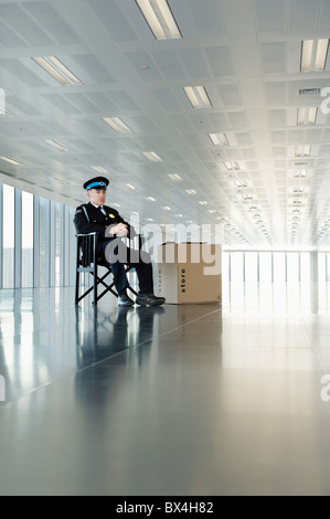 Uniformierte Wächter sitzen in leeren Büroflächen Stockfoto