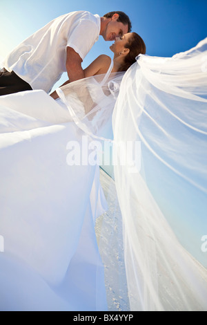 Ein verheiratetes Paar, Braut und Bräutigam, in der Sonne an einem wunderschönen tropischen Strand küssen Stockfoto