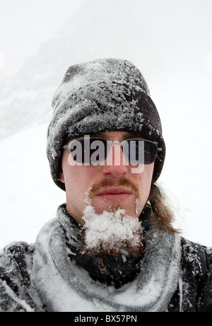 Porträt eines bärtigen Mannes Covers von Schnee in einem Schneesturm Stockfoto