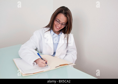 Lächelnde junge Ärztin arbeitet an einer Patientenakte Stockfoto