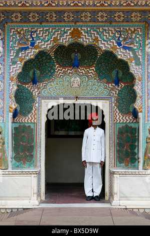 Mann in formalen weiße Indien Kleidung und roten Turban steht im Tor des Pfau-Tor, Stadtschloss, Jaipur, Rajasthan Stockfoto