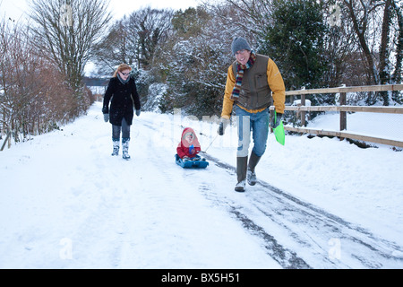 Junge auf einem Schlitten im Schnee, Hattingley, Hampshire, England, Vereinigtes Königreich gezogen wird. Stockfoto