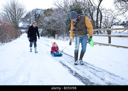 Junge auf einem Schlitten im Schnee, Hattingley, Hampshire, England, Vereinigtes Königreich gezogen wird. Stockfoto