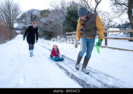 Junge auf einem Schlitten im Schnee, Hattingley, Hampshire, England, Vereinigtes Königreich gezogen wird. Stockfoto