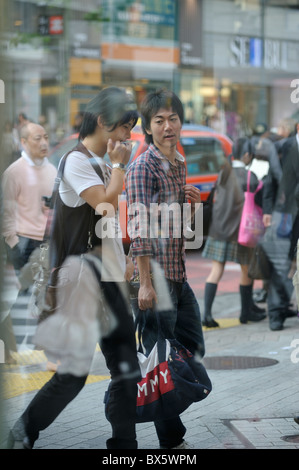 Zwei junge japanische Männer vorbei gesehen durch ein Fenster, Shibuya, Tokyo, Japan Stockfoto