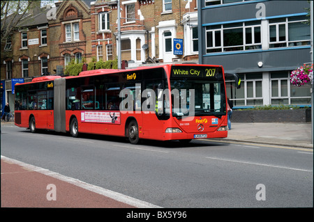 Ein Gelenkbus (biegsam) durchläuft auf dem Weg zur weißen Stadt in West-London Ealing. Es wird von ersten Busgruppe betrieben. Stockfoto