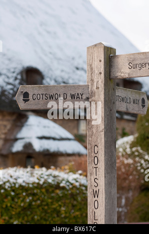 Cotswold Weise Wegweiser vor strohgedeckten Hütte im Winterschnee in Chipping Campden. Gloucestershire. England. Stockfoto