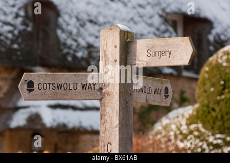 Cotswold Weise Wegweiser vor strohgedeckten Hütte im Winterschnee in Chipping Campden. Gloucestershire. England. Stockfoto