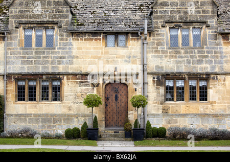 Abgeschnittene Box und Lorbeerbäumen vor einem Cotswold-Stein-Haus in Broadway, Worcestershire Stockfoto
