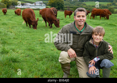 Vater und Sohn auf Bauernhof mit Kühen Stockfoto