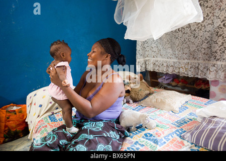 Eine junge Mutter hält ihr Baby Tochter beim Sitzen in ihrem Haus in Monrovia, Liberia, Westafrika. Stockfoto