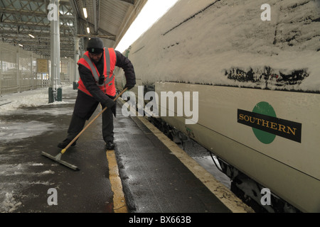 Eine Arbeitskraft löscht die Plattform der Schnee am Bahnhof Eastbourne, East Sussex, England. Stockfoto