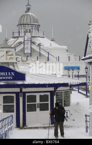 Ein Mann kämpft sich durch tiefen Schnee auf Eastbourne Pier, East Sussex, England. Stockfoto