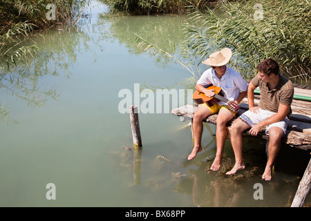 Zwei Männer sitzen im Chat auf See-Steg Stockfoto