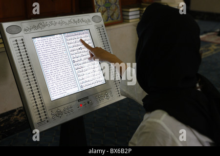 Frau liest eine Arabisch und Englisch elektronische Version des Heiligen Koran, Dubai, Vereinigte Arabische Emirate, Naher Osten Stockfoto