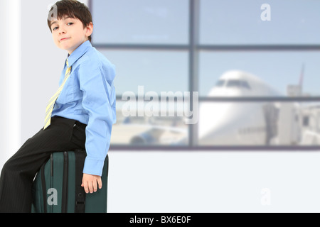 Entzückende sieben Jahre alten französischen amerikanischer Junge auf Koffer am Flughafen sitzen. Stockfoto