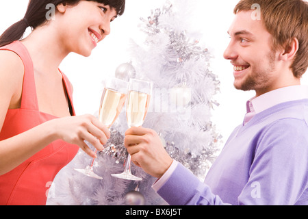Porträt des glücklichen Paares in Santa Mützen sahen einander während Toasten Stockfoto