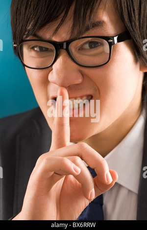 Porträt des jungen Geschäftsmann mit dem Finger in der Nähe von Mund Stockfoto