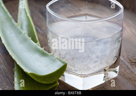 Glas mit Aloe Getränk und Blatt als Closeup auf altem Holz Stockfoto