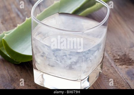 Glas mit Aloe Getränk und Blatt als Closeup auf altem Holz Stockfoto