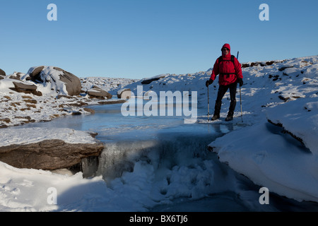 Ein Walker auf den zugefrorenen Fluss Kinder, Winter auf Kinder Scout im Dunkeln Peak Teil der Peak District National Park, Derbyshire Stockfoto