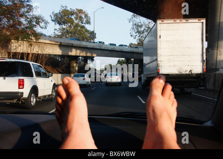 Füße auf dem Armaturenbrett eines Autos auf einer Autobahn. Los Angeles, Kalifornien, USA Stockfoto