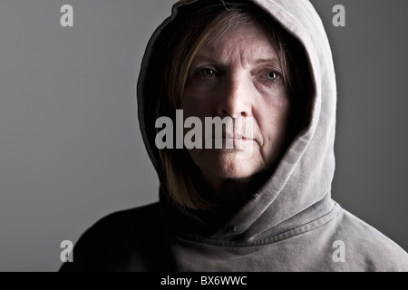 Schuss von Senior Lady in Kapuzenshirt vor grauem Hintergrund Stockfoto