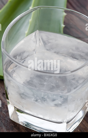 Glas mit Aloe Getränk und Blatt als Closeup auf altem Holz Stockfoto